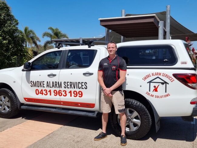 Myles 1 Smoke Alarm Services technician standing in front of work ute.